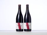 two bottles of red wine sitting next to each other on a table