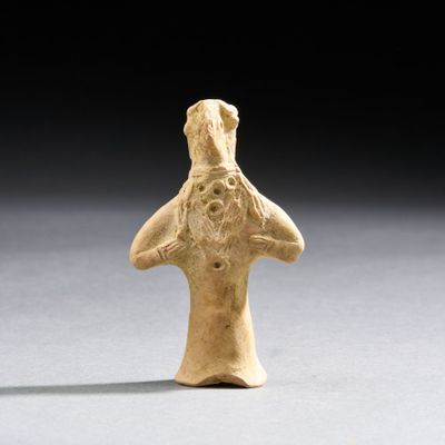 une vieille figurine représentant un homme qui porte ses mains à son visage