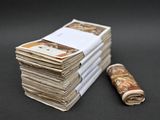 une liasse de billets posée à côté d'un rouleau de papier enroulé