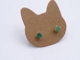 cat ear studs with green stones on top of a cardboard board
