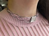 a close up of a woman wearing a pink sweater and a silver necklace