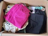 a cardboard box filled with clothes and a pink bag