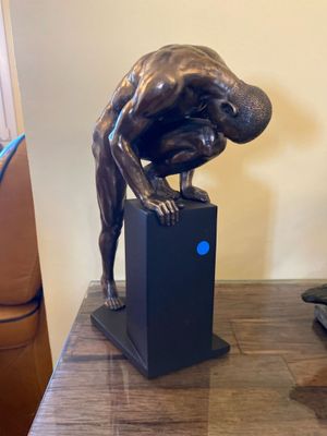 a statue of a man bending over on top of a box