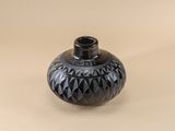 a black vase sitting on a table with a beige background