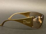 sunglasses with a gold frame and mirrored lens on a gray surface