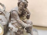 a statue of a woman sitting on a table next to a clock