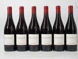 six bottles of red wine are lined up on a table