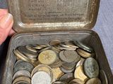 une personne tenant une boîte métallique remplie de pièces de monnaie