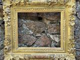 une photo représentant un cadre accroché à un mur en pierre