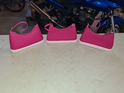 three pairs of pink shoes on a table next to a motorcycle