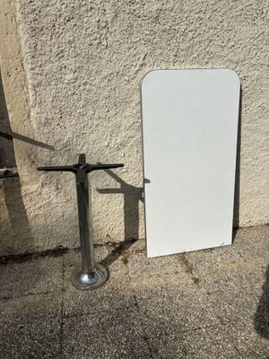 un tableau blanc appuyé contre un mur, à côté d'un poteau métallique