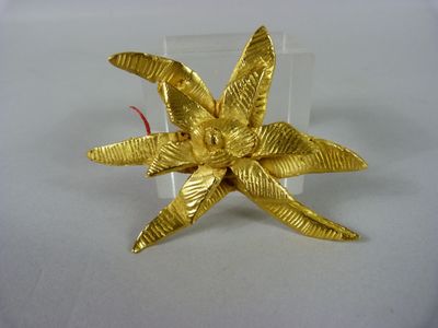une broche en forme de fleur dorée sur un fond blanc
