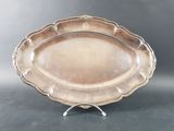 a large silver plate with a decorative design on a stand