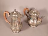 pair of antique silver teapots with wooden handles on a table