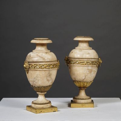 pair of antique marble urns on pedestal on grey background