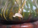a green vase with a brown base on a table