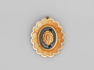 un gros plan sur une broche en pierre dorée et noire