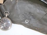 a silver pocket watch sitting on top of a brown bag