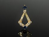 un gros plan d'un pendentif en or et diamants bleus posé sur une surface noire