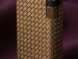 un gros plan d'un briquet doré posé sur un tissu violet