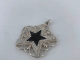 a close up of a silver and black star pendant on a white surface