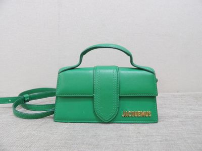 a green handbag with a small strap on a white surface