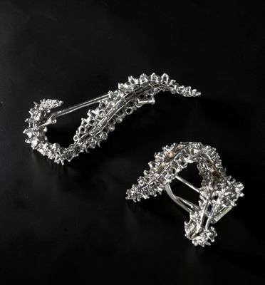 a close up of two silver hair clips on a black surface