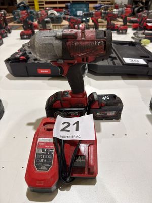 a red cordless drill on a table with other tools
