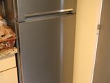 a stainless steel refrigerator in the corner of a kitchen