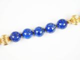 un gros plan d'un collier de perles bleues posé sur une surface blanche