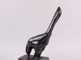a black sculpture of a bird sitting on top of a wooden block