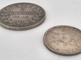 two silver coins sitting next to each other on a white surface