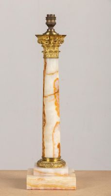 une colonne en marbre blanc et doré surmontée d'une bougie