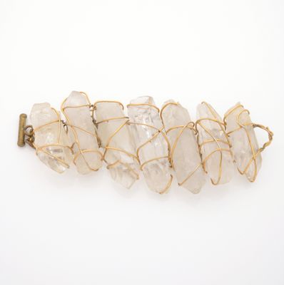 a close up of a gold wire bracelet with white crystals on it