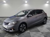 La Nissan Versa argentée est garée dans une pièce dont le sol est à carreaux.