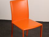 an orange chair sitting in a room with a white wall
