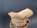 a brown and white vase sitting on a blue table