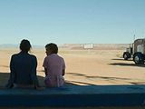 two people sitting on a bench in front of a semi truck