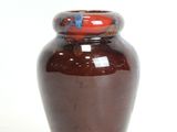 a brown vase with a red lid sitting on a white surface
