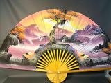 a fan with a painting on it sitting on a table