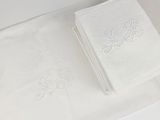 two white towels sitting on a white table with a pair of scissors