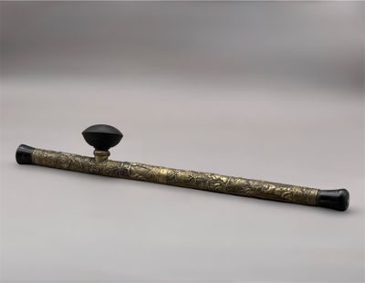 une pipe noire et dorée posée sur une surface blanche