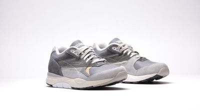 une paire de baskets grises et blanches posées sur une surface blanche