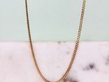 un collier à chaîne en or posé sur un comptoir en marbre
