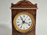 une petite horloge en bois avec des chiffres romains