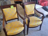une paire de fauteuils rembourrés jaunes dans une pièce où se trouve une étagère remplie de livres