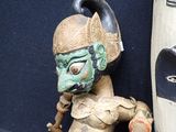 a statue of a man holding a stick next to a mask