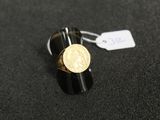 Gros plan sur une bague ornée d'une pièce d'or