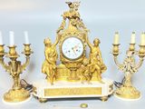 une horloge en or posée sur une table, à côté de bougies