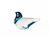 un oiseau en verre posé sur une surface blanche